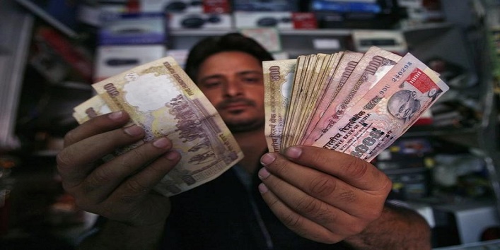 A shopkeeper poses for a picture as he counts Indian currency notes at his shop in Jammu May 16, 2012. REUTERS/Mukesh Gupta/Files