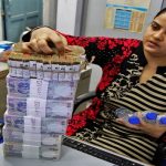 A cashier stacks Indian currency notes inside a bank in Chandigarh