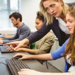 Attractive teacher helping her student in computer class