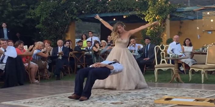 Groom hangs in the air after being kissed by the bride cover