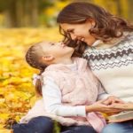 Mom and daughter having fun in autumn park.